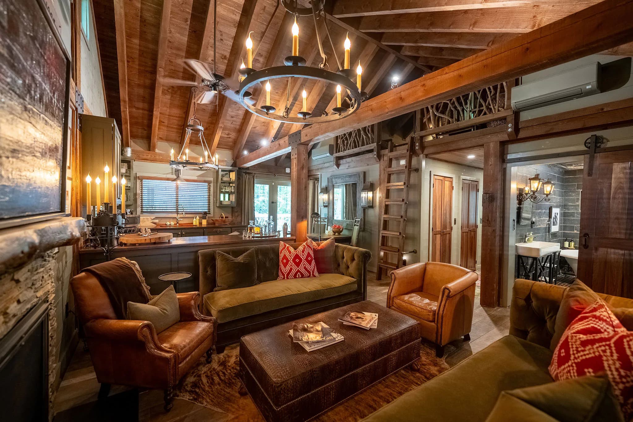 Candlelit chandelier and loft ladder in the timber-beamed great room of a Jones Gap cabin rental