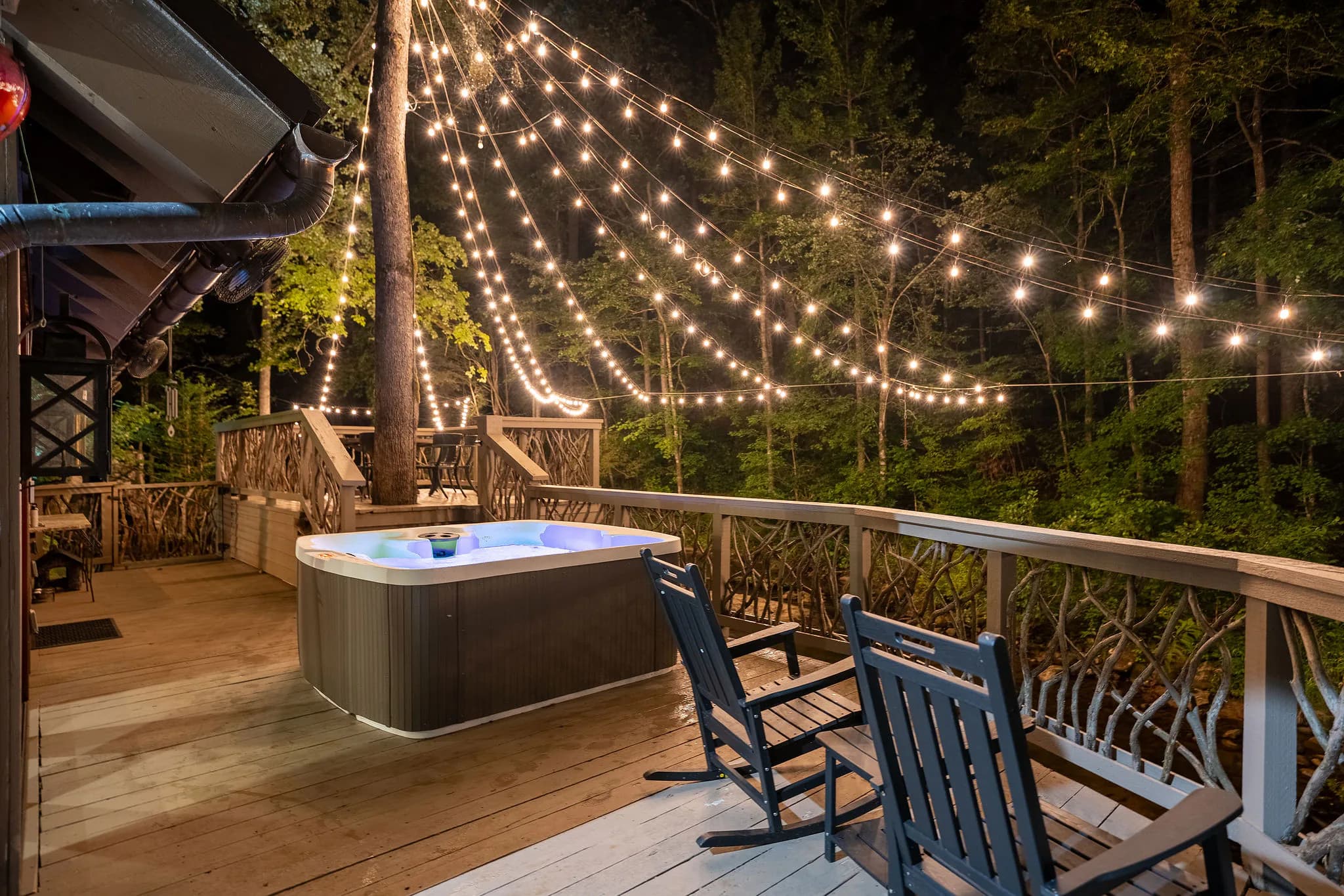 Private hot tub glowing under a canopy of string lights on the deck of a riverfront cabin in Marietta SC