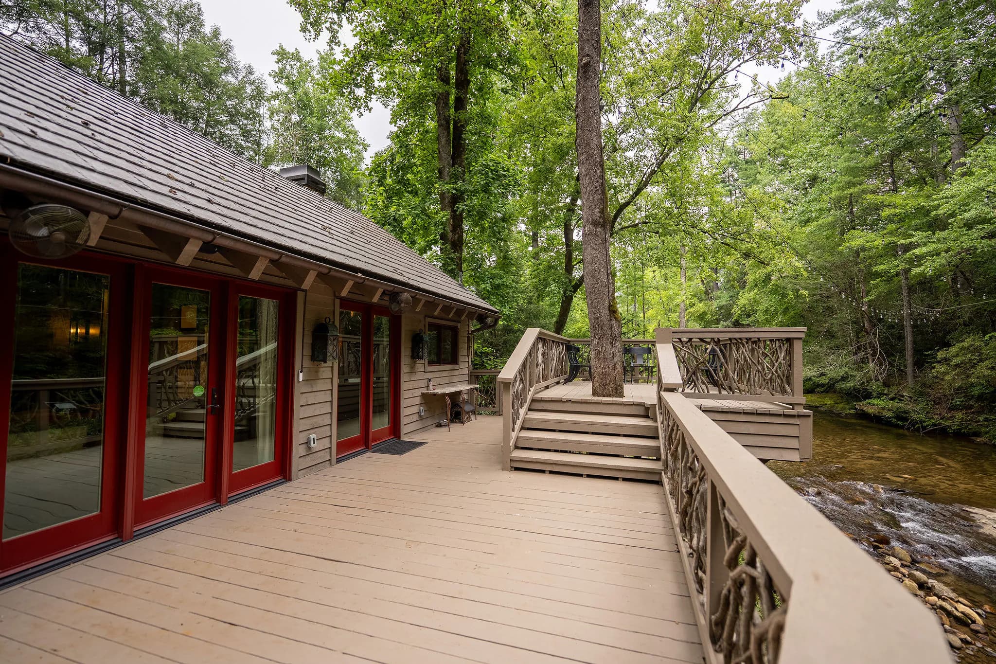 Riverfront deck with red French doors and branch railings above the Middle Saluda River in South Carolina