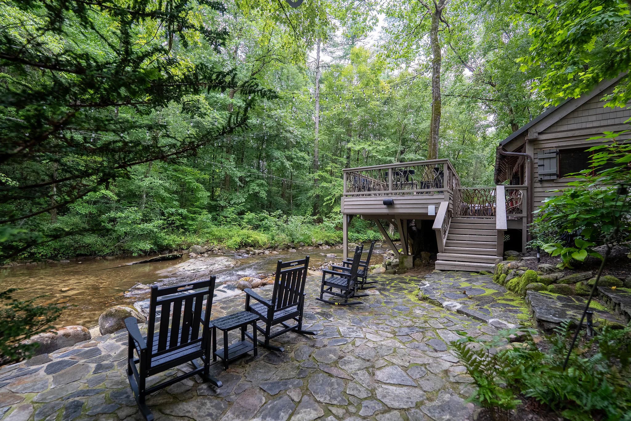 Rocking chairs on a stone patio at the edge of the Middle Saluda River at a Marietta SC cabin