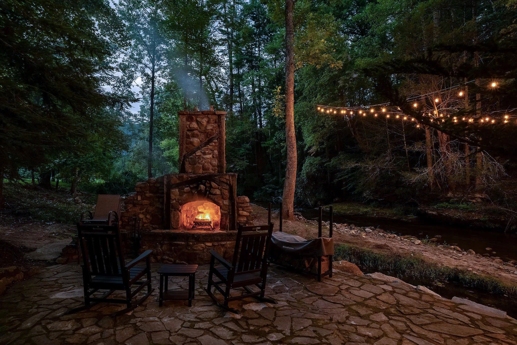 Stone patio and wood burning fireplace beside the river at a Jones Gap cabin rental